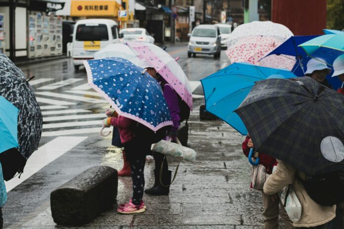 Photo by Adrien Bruneau people holding umbrella on sidewalk