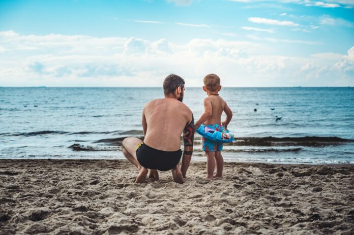 Photo by Jan Kopřiva man in black shorts holding blue plastic bucket on beach during daytime