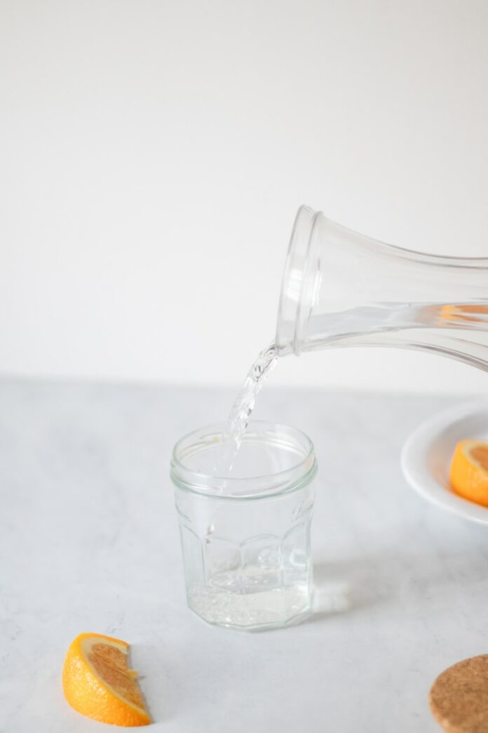 Photo by Fiona Murray-deGraaff A pitcher pouring water into a glass filled with orange slices