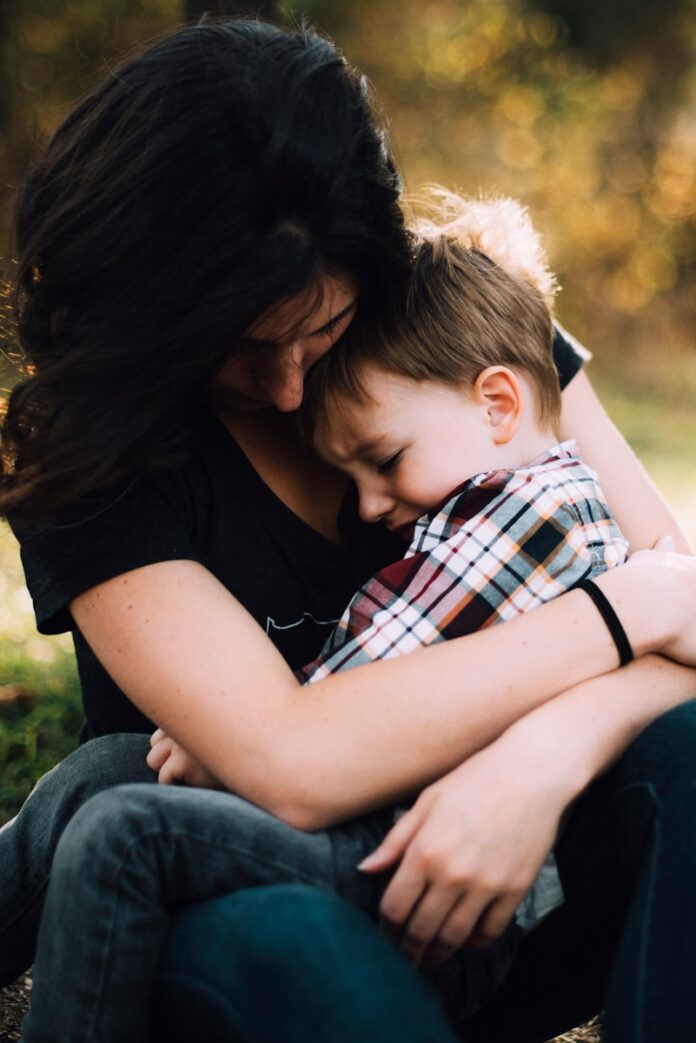 Photo by Jordan Whitt woman hugging boy on her lap