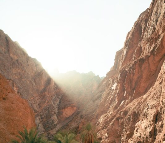 건강과 다이어트를 위한 야외 활동 a man walking down a dirt road next to a mountain