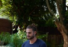 건강을 지키는 비법 a man sitting on a yoga mat in the middle of a garden