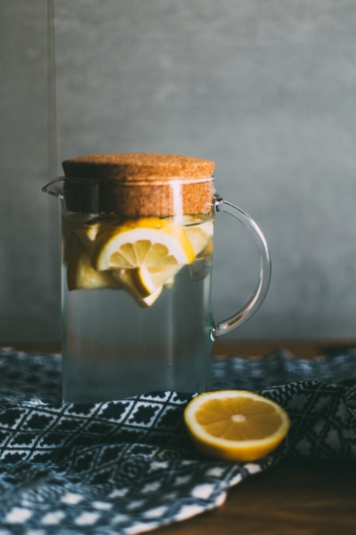 Photo by Daiga Ellaby clear glass pitcher filled with sliced lemons on black and white table runner