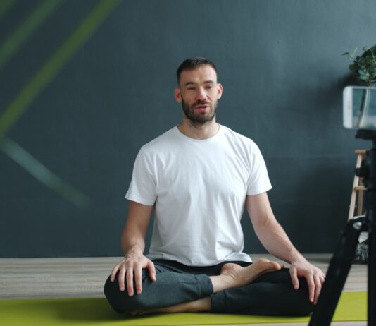 필라테스, 일상 속 건강한 움직임으로 자리잡다 Man meditating on yoga mat recording with phone.