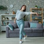 늘어나는 집콕 생활, 건강 지키는 ‘홈 웰니스’ 습관이 뜬다 Young woman dancing in a modern living room.