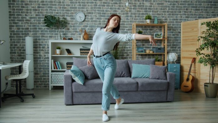 Photo by Vitaly Gariev Young woman dancing in a modern living room.