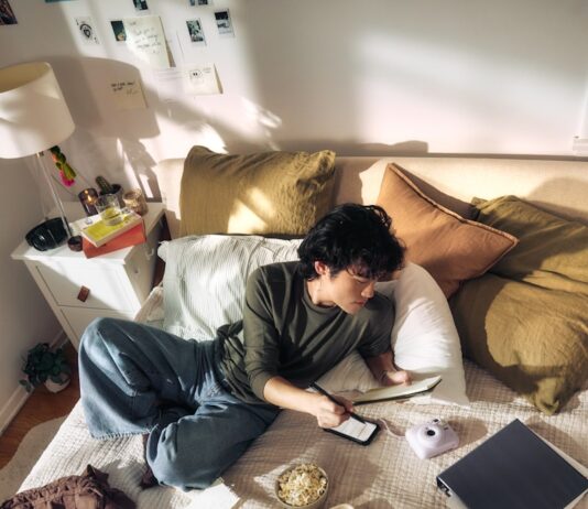 집에서도 실천하는 ‘슬로우 라이프’, 작은 변화가 건강을 바꾼다 Young man on bed with laptop and snacks